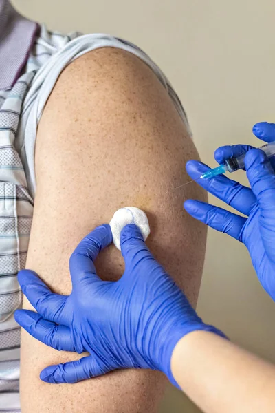 Bir doktor, klinikte bir adamı koronavirüse karşı aşılıyor. Yakın plan. Covid-19 'a karşı aşı, aşı, aşı, önleme kavramı