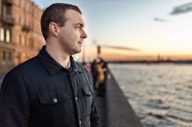 Nehrin kenarında gün batımını izleyen genç bir adamın portresi..