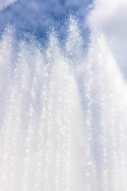 Su fıskiyelerinin ve fıskiyelerin arkaplanı bulutlu mavi gökyüzüne çarpıyor..