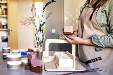 Sabun üreticisi bir kız elinde yeni demlenmiş bir sabun tutuyor. Yemek pişirme süreci. Ev spa 'sı. Alışveriş merkezi işi.