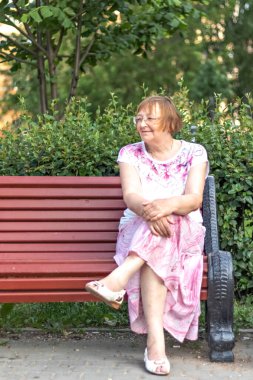 Bankta gülümseyen yaşlı bir kadının portresi..