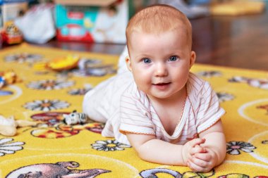 Küçük bir çocuk oyuncakların arasında halıda.
