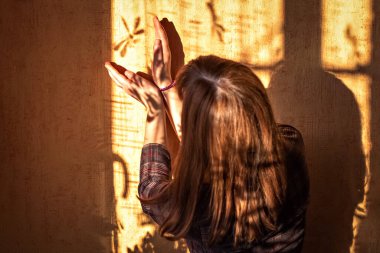 Genç bir kadın duvarda bir yusufçuğun gölgesini yakalıyor..