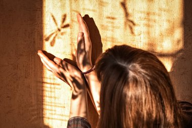 Genç bir kadın duvarda bir yusufçuğun gölgesini yakalıyor..