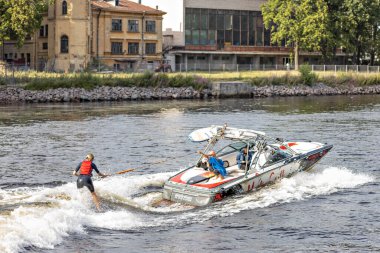 Genç bir kadın nehirdeki bir tekneye bağlı bir su tahtasına biniyor..