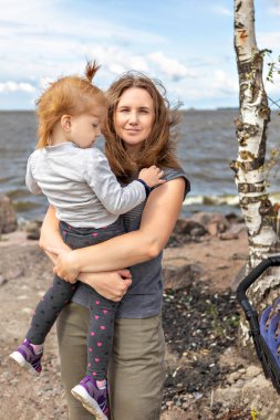 Annesinin kucağında küçük bir kızı sahilde sarılıyordu..