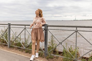 Bulutlu bir akşamda genç bir kadın setin üzerinde duruyor..