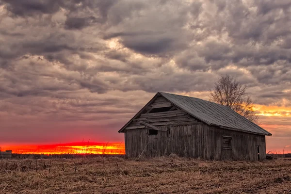 Słońce zachodzi za stary dom stodoła — Zdjęcie stockowe