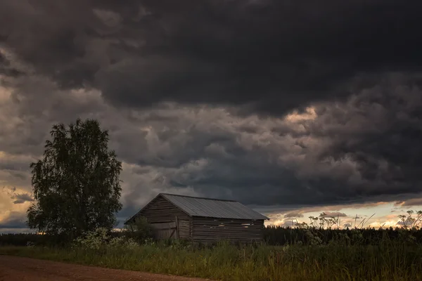 Kleine schuur en een Birch Tree onder de donder wolken — Stockfoto