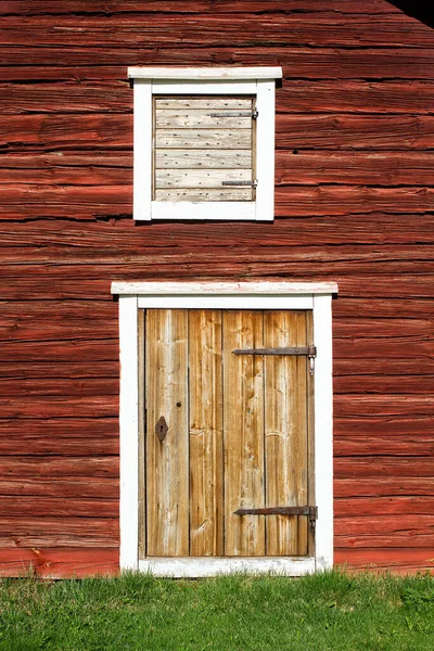 古い木造農場の建物の壁に木製のドアの上に古いハッチ 壁は伝統的な方法で赤く塗られています — ストック写真