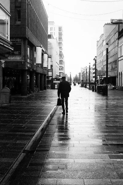 An old man is walking in the rain at Oulu, Finland. The springtime weather can be very wet in the coastal towns of Finland.