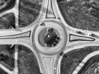 İnsansız hava aracının bakış açısından bir döner kavşak. Girip çıkan bir kaç araba var. Sonbahar güneşi etrafındaki tarlalara uzun gölgeler bırakır..