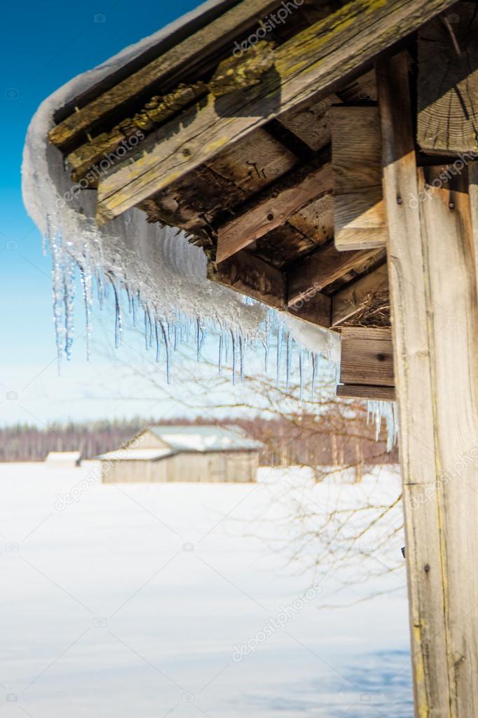 Icicles Hanging On An Old Barn House Roof