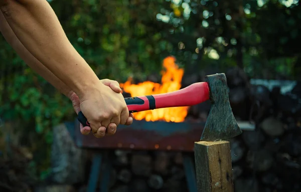 Homem cortando madeira em um fundo de fogo — Fotografia de Stock