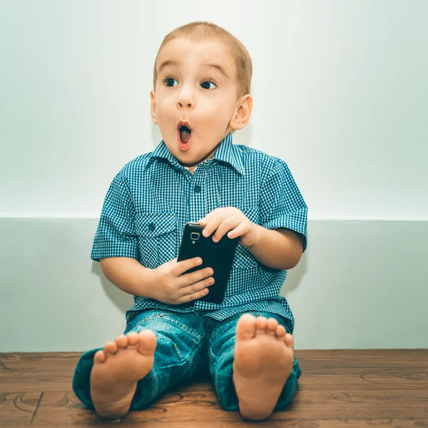 Niño sorprendido con un teléfono celular Fotos De Stock