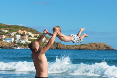 Man and child. Father and son playing on the beach. clipart