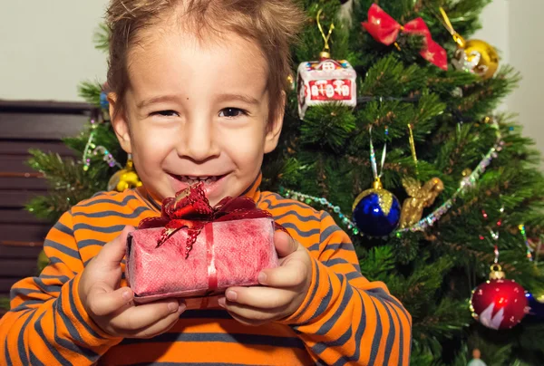Weihnachtsporträt eines glücklichen Kindes mit Geschenk. — Stockfoto