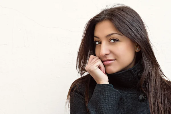 Portrait of beautiful young dark-haired woman on wall background — Stock Photo, Image