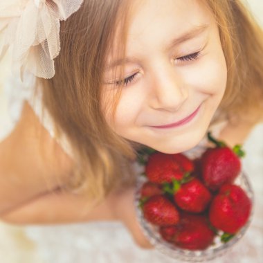 Çilek seviyor oldukça küçük bir kız portresi.