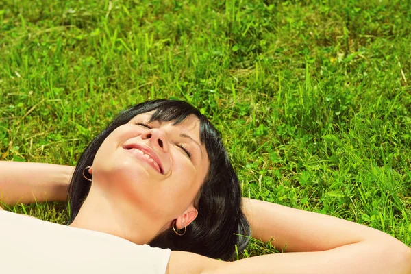 Schöne, glückliche junge Frau im Gras liegend — Stockfoto