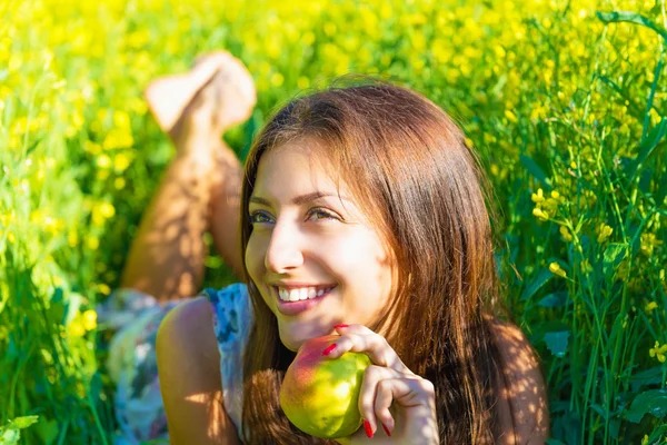 Portrait of a beautiful smiling woman with an apple in nature — Stockfoto