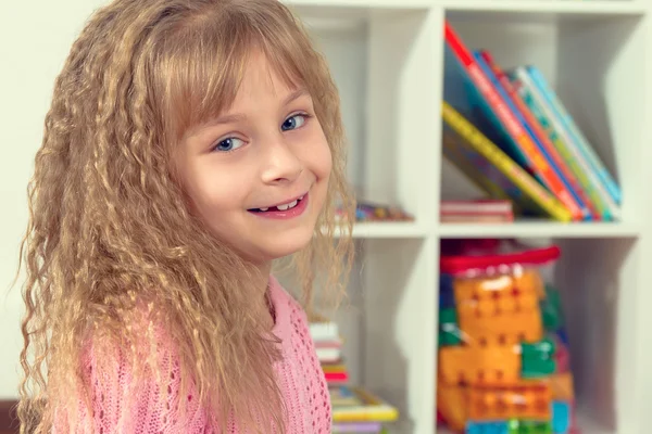 Retrato de una hermosa niña sonriente en la habitación de los niños . — Foto de Stock