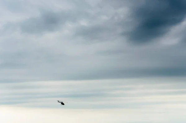 在乌云密布的天空中低空飞行的轮廓直升机 — 图库照片