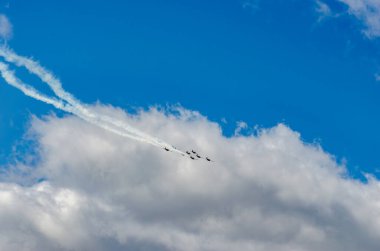 Avcı jetleri bulutlarla dolu bir gökyüzünün önünde uçuyor. Arkalarında da kalın bulutların önünde iki jet yolu var..