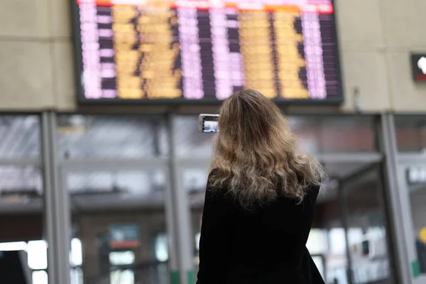 Kız tren ya da uçak saatlerini izliyor.