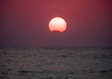 Büyük güneş denizin üzerinde batıyor. Gün doğuyor, kızıl gökyüzü.