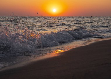 Denizin ve kumsalın üzerinde gün doğumu