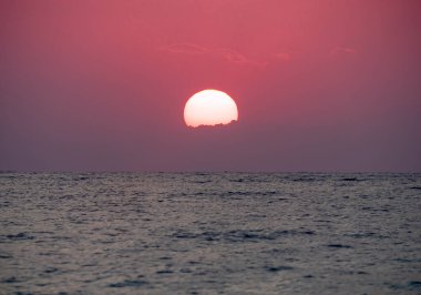 Büyük güneş denizin üzerinde batıyor. Gün doğuyor, kızıl gökyüzü.