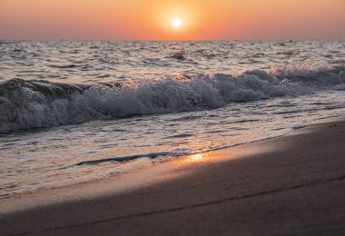 Denizin ve kumsalın üzerinde gün doğumu