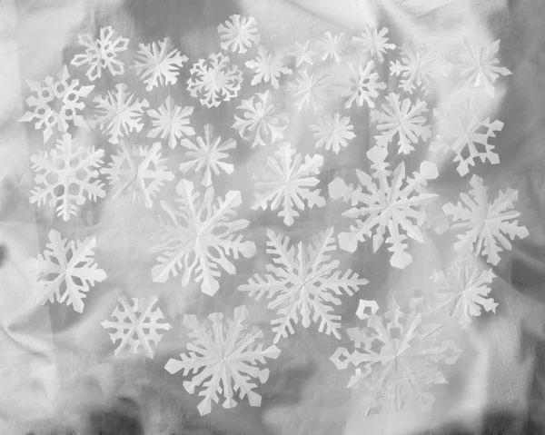 Flocos de neve de papel sobre fundo pano brilhante — Fotografia de Stock