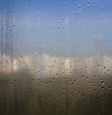 Doğal su damlaları doğanın arka planında pencere camına düşer.