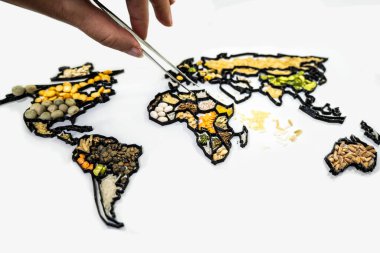 Bir el cımbızla çeşitli gıda ve baharatlardan yapılmış bir dünya haritasını yeniden düzenliyor.