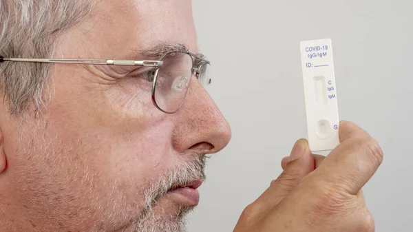 Mężczyzna Okularach Trzymający Przed Sobą Test Odporności Covid — Zdjęcie stockowe