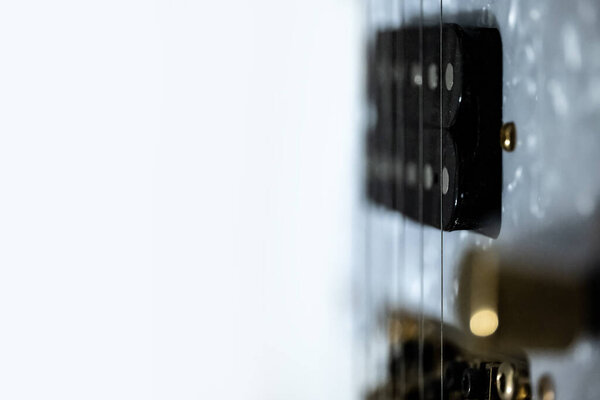 Close up of an electric guitar showing double coil pickup and E string with white background at one side for text