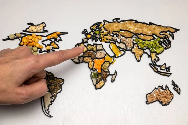 Pointing to a world map made of various food ingredients and spices. New world order, the great reset