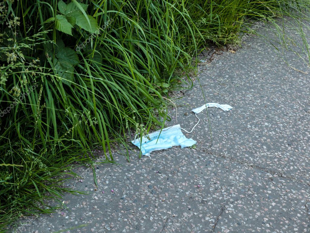 Desechada mascarilla usada, rasgada y sucia en el suelo de hormigón con ...