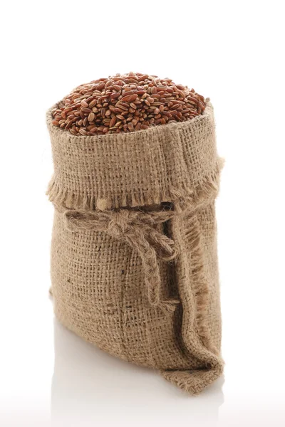 Braunes Reiskorn "devzira" in einem Sack auf weißem Hintergrund — Stockfoto