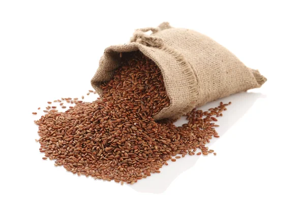 Grade brown rice grain "devzira" razbrossany near the bag on a w — Stock Photo, Image