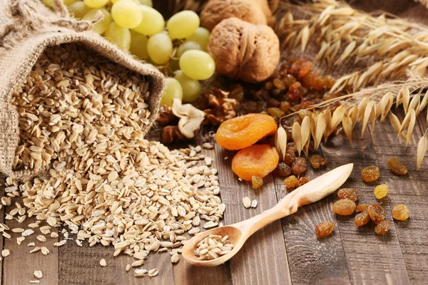 Harina de avena en saco, orejas de avena, albaricoques secos, pasas, uvas , — Foto de Stock