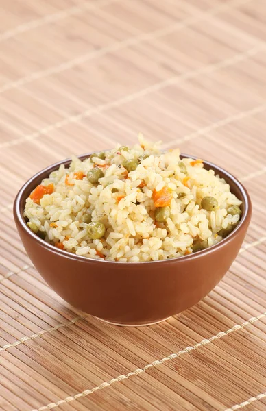 Rice with vegetables in a ceramic bowl on a mat — Stock Photo, Image