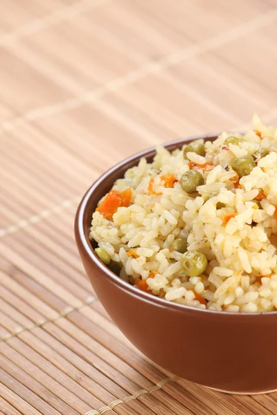 Arroz com verduras em um boliche cerâmico em um tapete — Fotografia de Stock