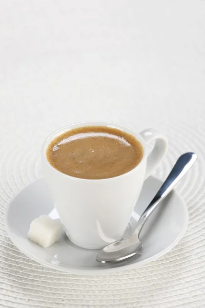 Tazza di caffè in un piattino con un cucchiaio su vimini bianco un tappetino — Foto Stock