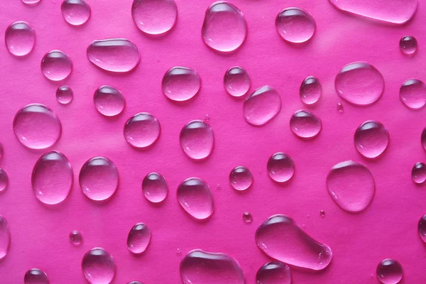 Gocce d'acqua su fondo rosa — Foto Stock