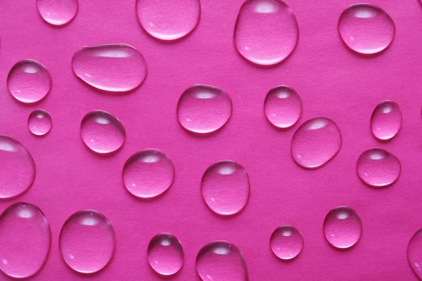 E gocce d'acqua su fondo rosa — Foto Stock