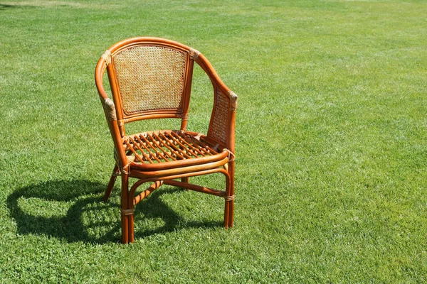Cadeira de vime no fundo da grama fresca — Fotografia de Stock