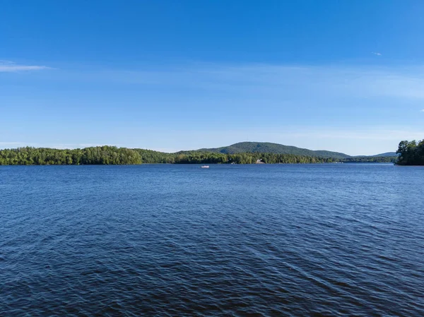 Kanada göl manzaralı küçük bir tekne. Yazın gölün kenarında orman ve dağlar var.
